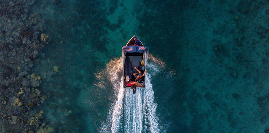 An overhead view of a boat cruising over deep blue water.