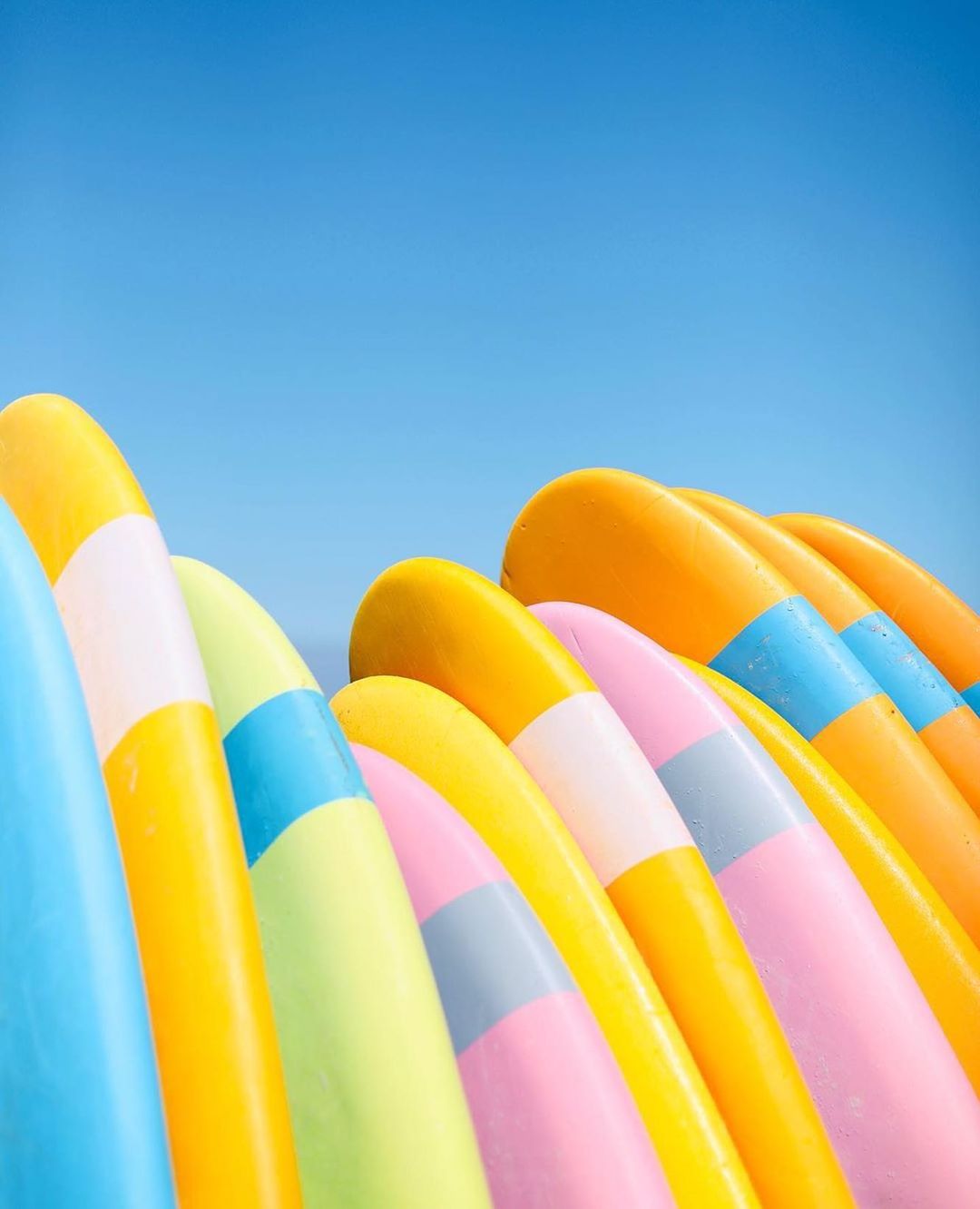 Brightly colored surfboards against a bright blue sky.
