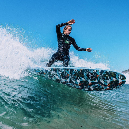 Kyuss riding a wave on a surf board with a leaf pattern.