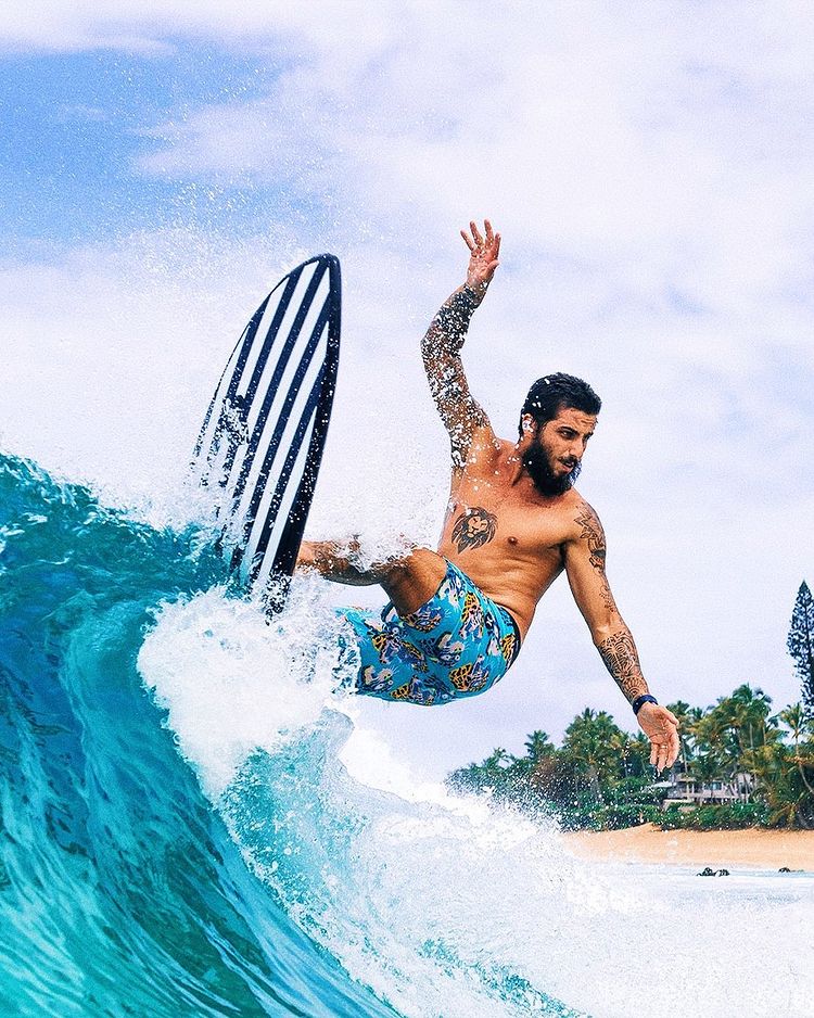 A man wearing blue shorts surfs a big wave.