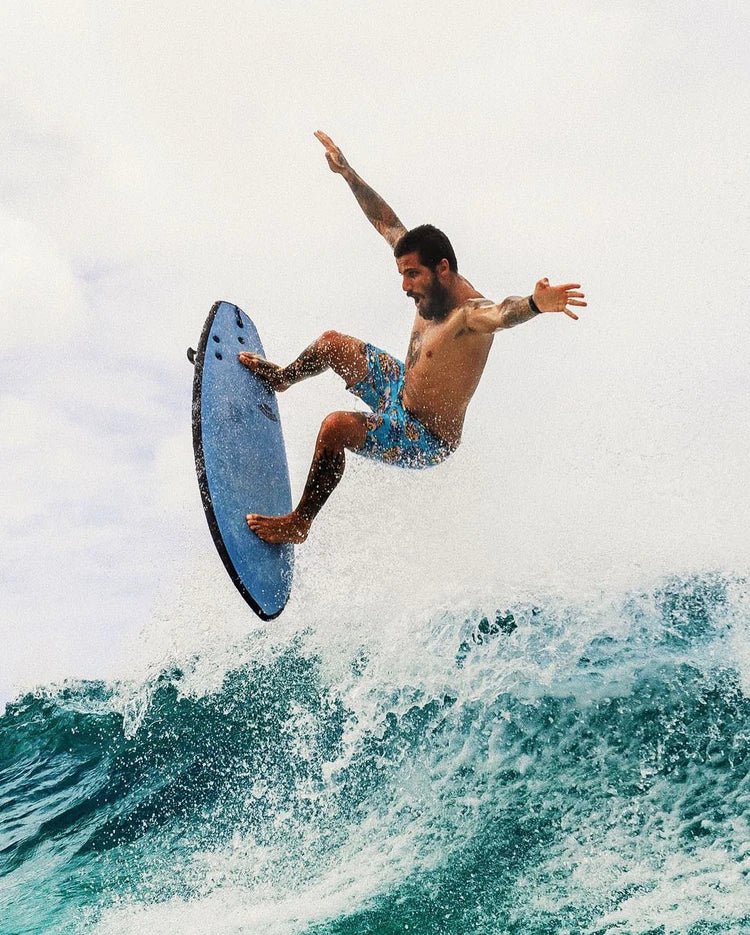 A man performs tricks on a blue surf board.